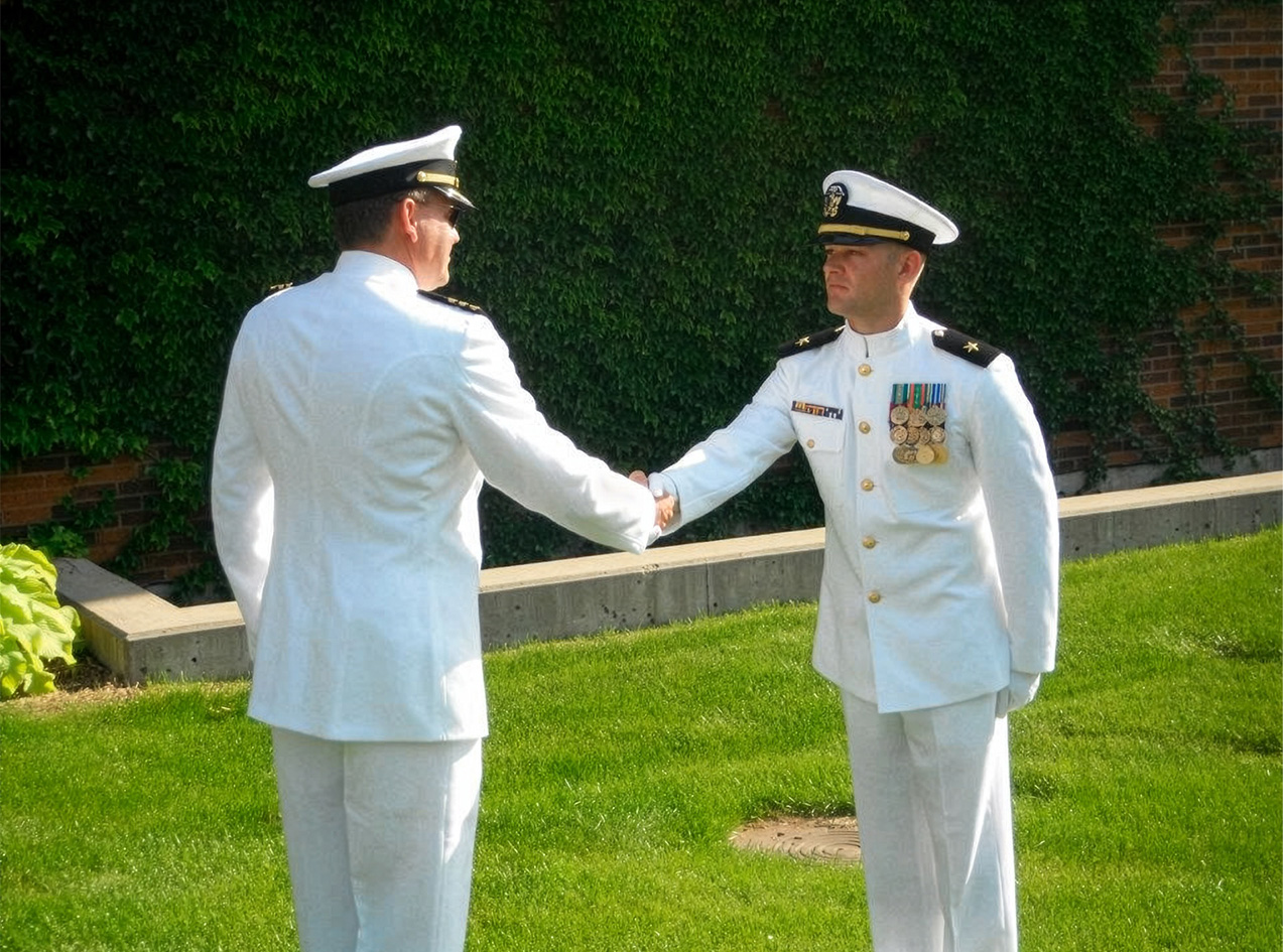 Adam Schwarze in uniform shaking hands with another Navy Officer.